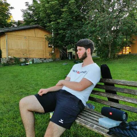 Jugendlicher entspannt auf einer Bank vor der Hütte