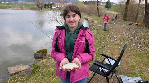 Jungfischerin mit Fisch neben ihrem Angelplatz