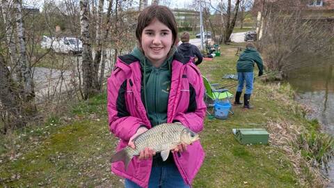 Jungfischerin in pinker Jacke mit Fisch am Furthweiher