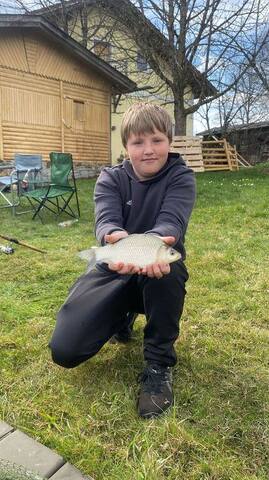 Junge mit Fisch vor der Hütte am Furthweiher