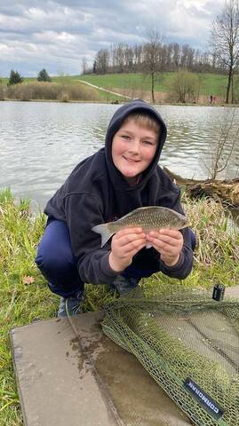 Junge mit Fisch auf der Abhakmatte